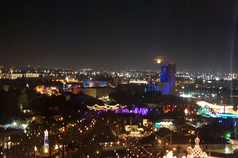City lights at night from a hilltop: a wide spread of streetlights and buildings under a dark sky.